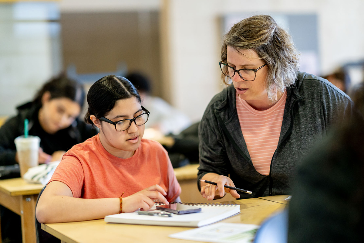 Female instructor assisting female student in classroom.