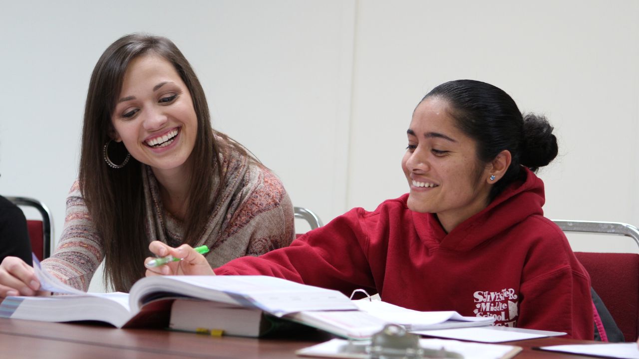 Student receiving help from a tutor while looking together at a textbook