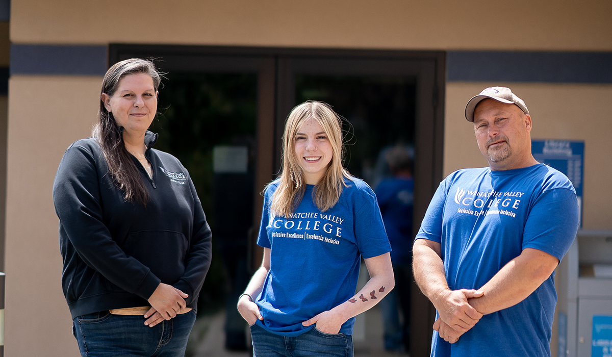 Two woman and man standing outside of building.