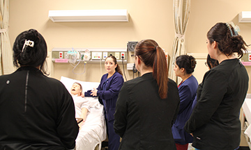 Professor Carolina Martinez Calderon demonstrates a medical procedure for her students using a manikin.